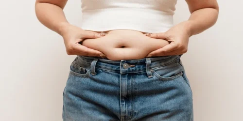 Woman pinching belly fat jeans 600nw