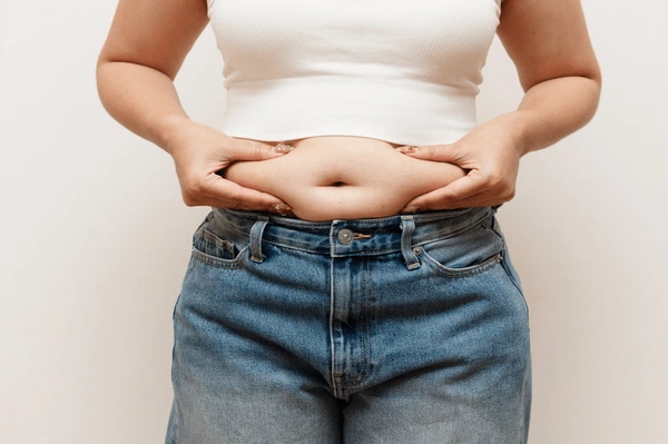 Woman pinching belly fat jeans 600nw